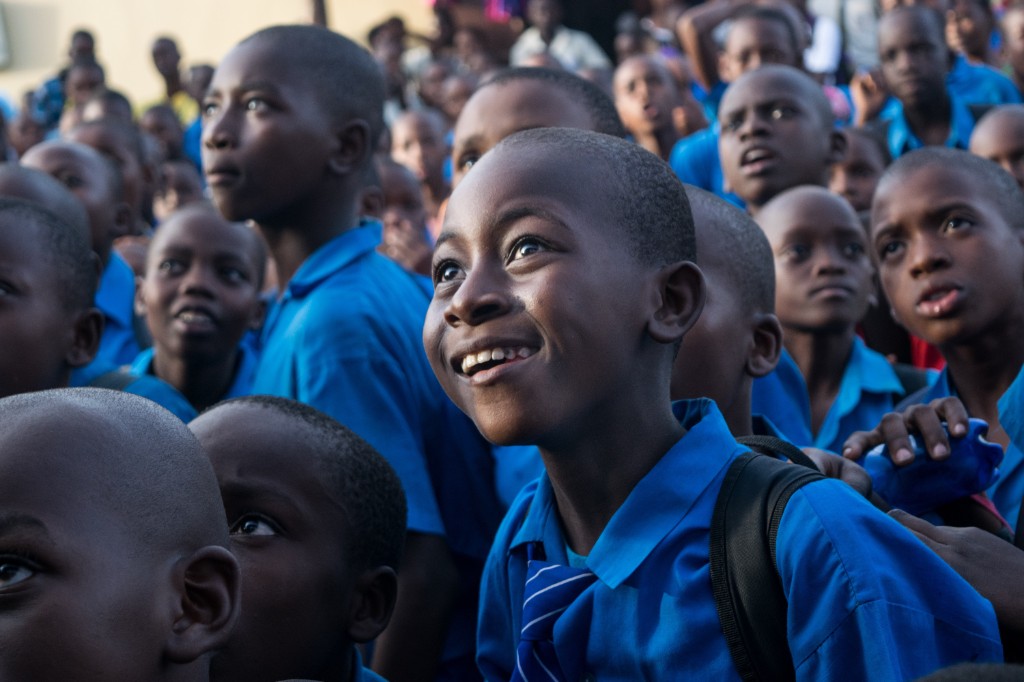 Schoolchildren in blue uniforms gathered outdoors, looking upward